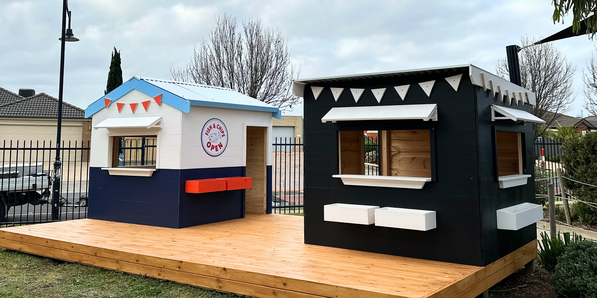 Image of 2 timber cubby houses styled as a Fish n Chip shop and Farmers market. Installed at Derrimut Primary School in Victoria