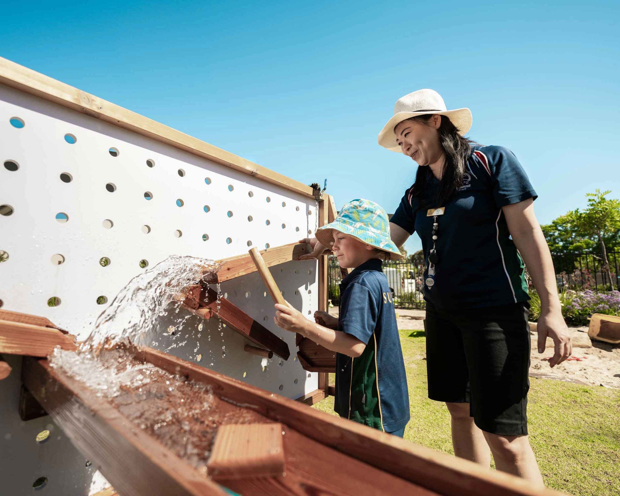 A child and teacher playing on a water wall learning STEM skills